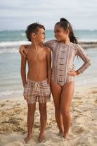 Two children standing on a beach with ocean in the background